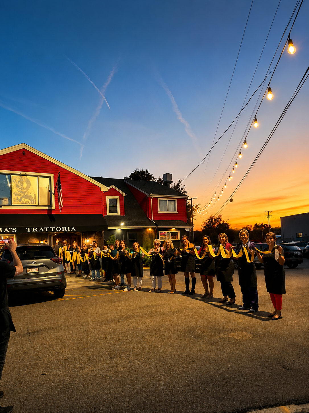 Class group holding fresh pasta at sunset outside Maria's Trattoria