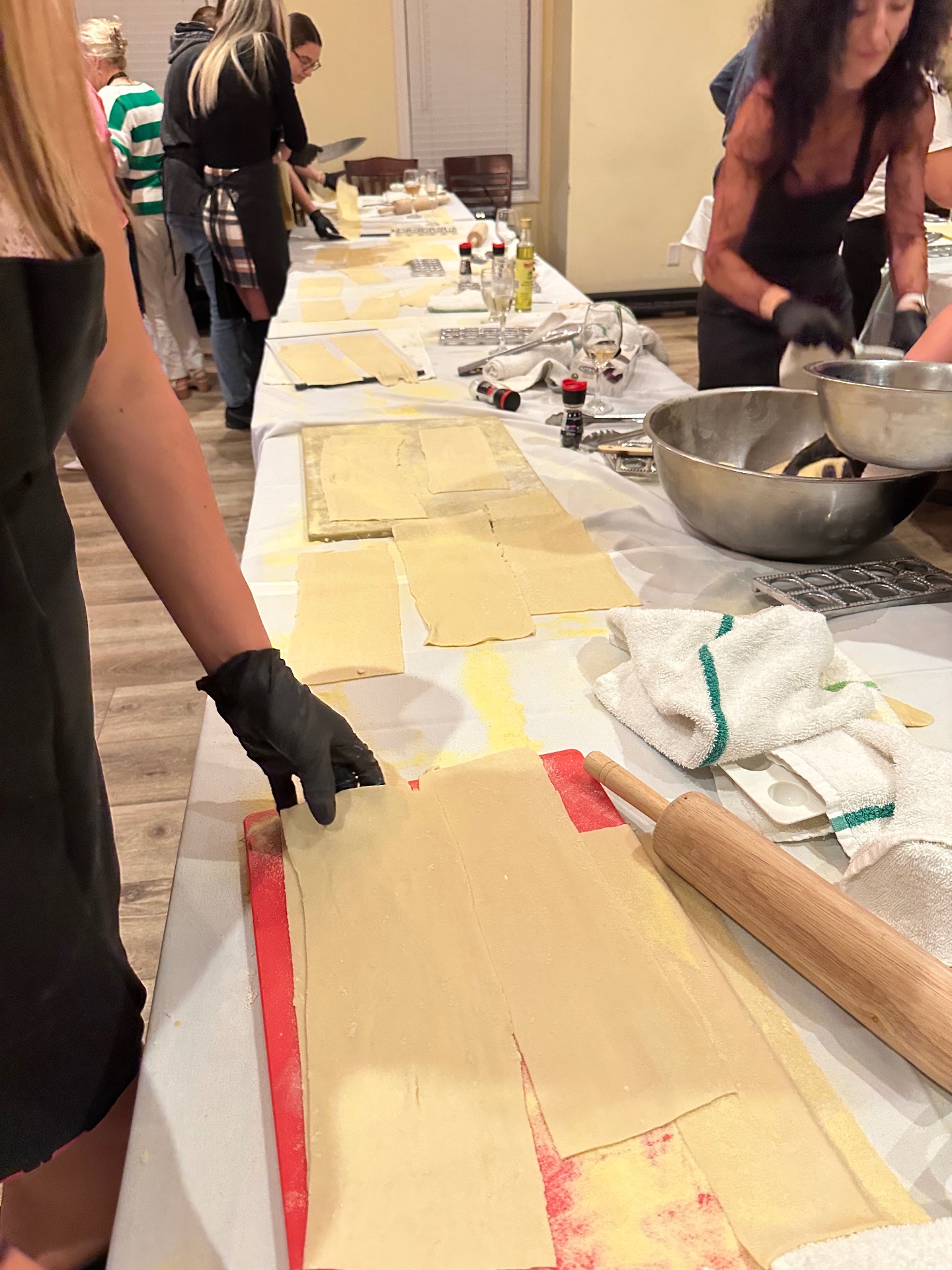 Hands rolling and cutting fresh pasta dough along the prep table