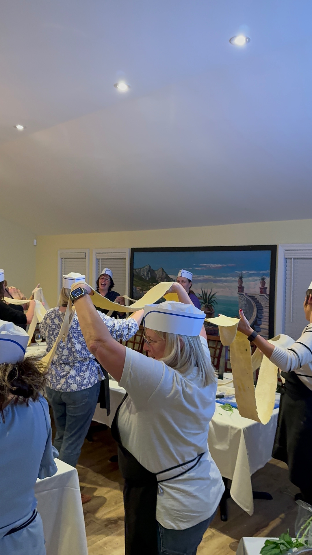 Guests holding up long ribbons of fresh pasta together