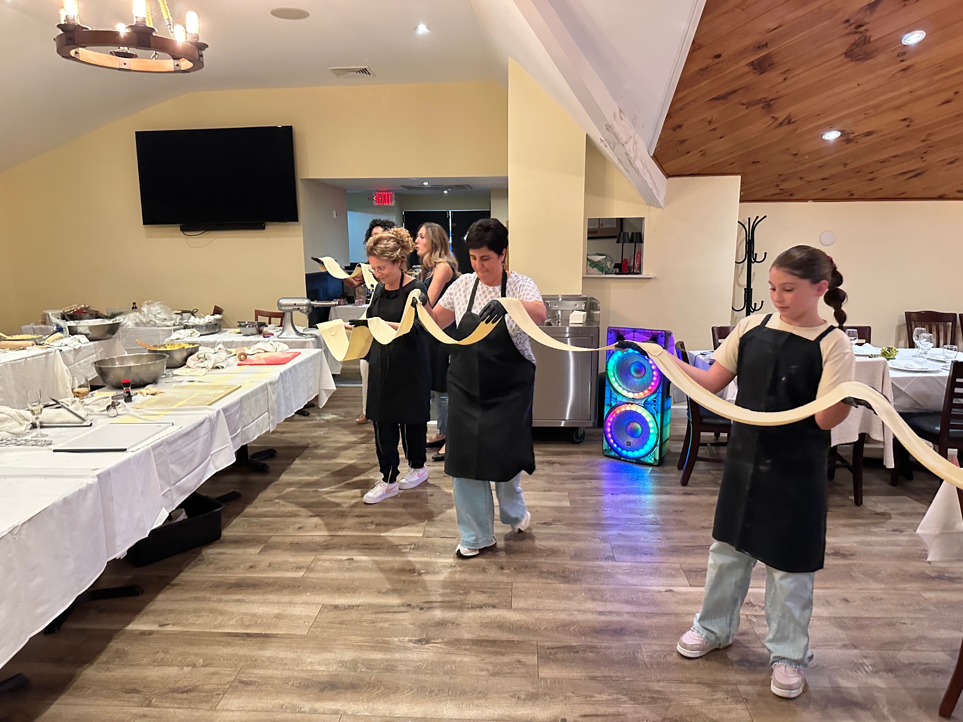 Guests stretching long fresh pasta ribbons across the dining room at Maria's Trattoria
