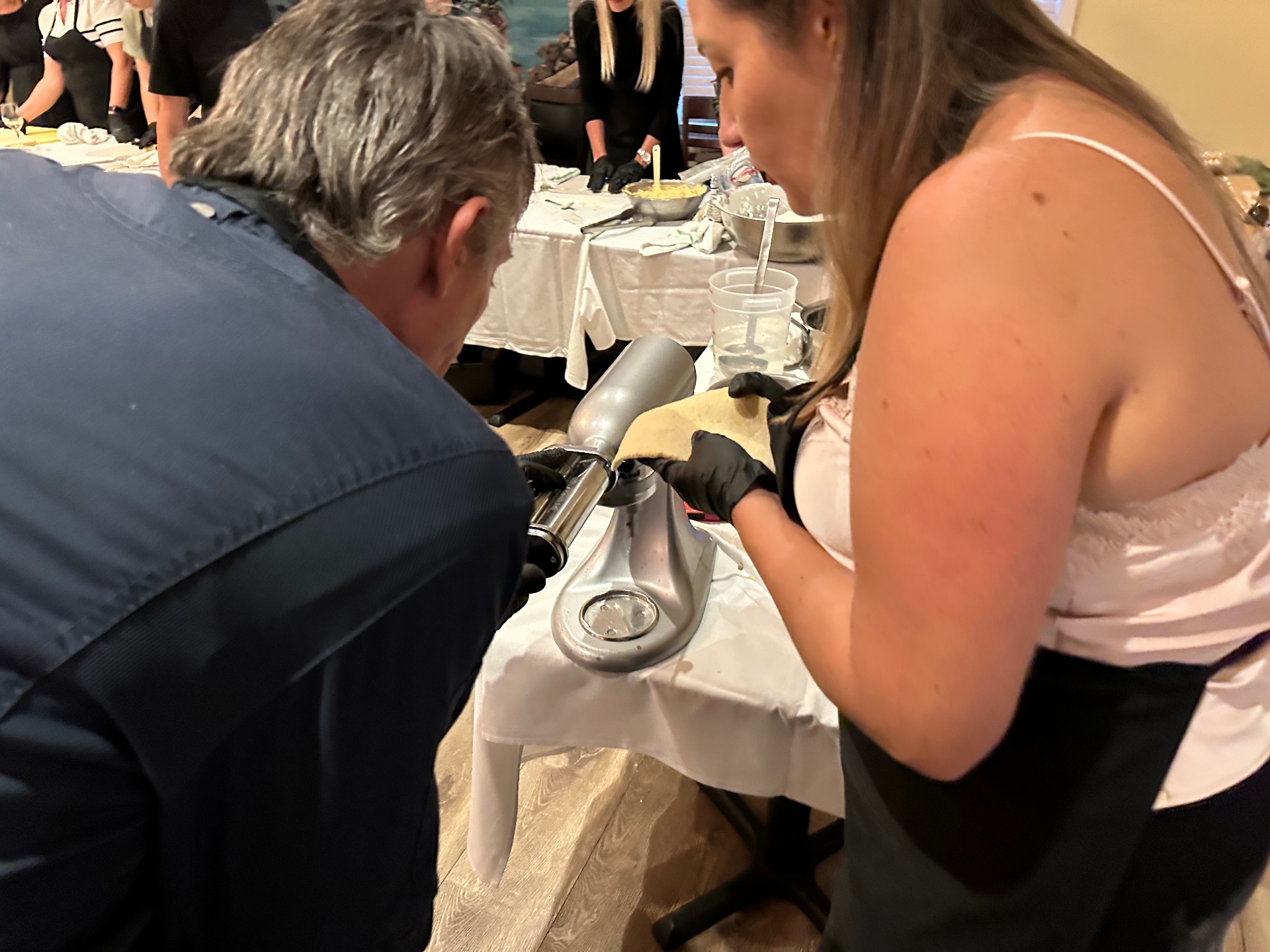 Guests working the pasta press together during a hands-on cooking class